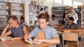 Positive teenage schoolers reading and writing Royalty Free Stock Photo