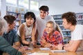 Positive teenage students working and discussing in groups in library Royalty Free Stock Photo