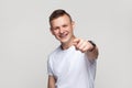 Positive teenager boy looking at camera with toothy smile, pointing at camera with finger, choosing Royalty Free Stock Photo