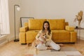 Positive teenager sits on living room floor and plays with beloved dog with smile. Royalty Free Stock Photo