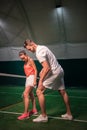 Positive tennis instructor teaching young woman