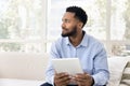 Positive thoughtful young African American man using digital tablet Royalty Free Stock Photo