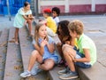 Positive tweenagers friendly blabbing while sitting on steps outdoors