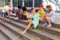 Positive tweenagers friendly blabbing while sitting on steps outdoors