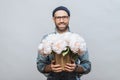 Positive unshaven male wears spectacles, holds beautiful bouquet of flowers, going to present them to his wife and congratulate wi