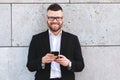 Positive urban business professional man in stylish suit using smartphone while standing outside Royalty Free Stock Photo