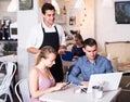 Positive waiter is greeting visitors and taking order.