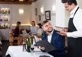 Positive waiter taking order in restaurant, helping young male