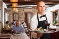 Positive waiter with tray at restaurant