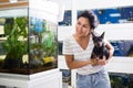 Positive woman with dog in her arms choosing aquarium fish at pet shop Royalty Free Stock Photo