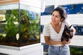 Positive woman with dog in her arms choosing aquarium fish at pet shop Royalty Free Stock Photo