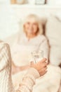 Positive woman giving glass of water for ill mother Royalty Free Stock Photo