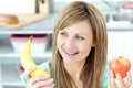 Positive woman holding a banana and an apple