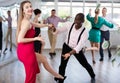 Woman and man dancing foxtrot in pair during group dance party