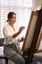 Positive woman painting picture with watercolor at cozy home. Art, creative hobby and leisure activity concept Royalty Free Stock Photo