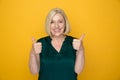 Positive woman showing thumb up isolated over the yellow background.