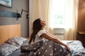 Positive woman sitting in bed and enjoying morning time Royalty Free Stock Photo