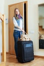 Positive woman with suitcase near door