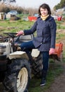 Positive woman working on small farm tractor Royalty Free Stock Photo