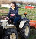 Positive woman working on small farm tractor Royalty Free Stock Photo