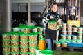 Positive woman working at the warehouse, stacking plastic containers with the selected olives