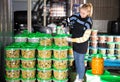 Positive woman working at the warehouse, stacking plastic containers with the selected olives