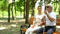 Positive woman and blind man spending time on bench in park, support and care