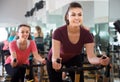 Positive women of different age training on exercise bikes Royalty Free Stock Photo