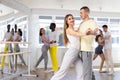 Couple in sportswear enjoying slow foxtrot in dance studio