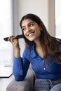 Positive young adult Indian girl listening to audio on phone Royalty Free Stock Photo