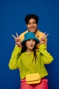 Positive asian couple showing peace sign while posing isolated over blue wall Royalty Free Stock Photo
