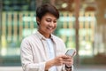 Positive asian guy using cell phone outdoors Royalty Free Stock Photo