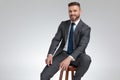 Positive young businessman smiles while sitting on a stool Royalty Free Stock Photo