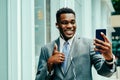 Positive young businessman using smartphone outside wearing suit