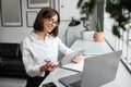 Positive young businesswoman working with digital tablet and laptop, sitting at desk in cozy office or cafe Royalty Free Stock Photo