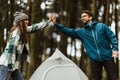 Positive young caucasian couple in jackets, enjoy travel vacation, make tent, give high five