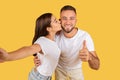 Positive young caucasian lady in white t-shirt kiss man in check, have fun, enjoy date, show thumb up