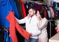 Young couple choosing together modern skiwear in sport shop