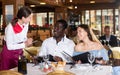 Positive young couple making order at restaurant Royalty Free Stock Photo