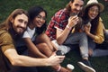 Two couples smiling and looking at you while sitting on the grass