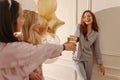 Positive young diverse girls clink paper cups at pajama party home.