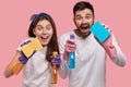 Positive young family couple have positive facial expressions, use chemical washing spray and sponge for cleaning Royalty Free Stock Photo