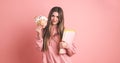 Happy young female student displaying scholarship money with book in pink Royalty Free Stock Photo