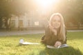 Positive young female student lying on the grass in the college park looking at the camera. Joyful student girl lying on the lawn Royalty Free Stock Photo