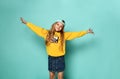 Pretty fashionable young teenager with a lovely smile posing in a baseball cap and yellow hoodie on a blue background Royalty Free Stock Photo