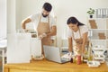 Positive young food delivery service workers working with online orders packing healthy meals in boxes