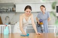 Young girl cleaning the table surface, mother vacuum-cleaning in the kitchen Royalty Free Stock Photo