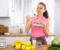 Positive young girl eating vegetable salad in home kitchen Royalty Free Stock Photo