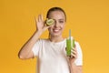 Positive young girl holding kiwi fruit and glass of fresh juice