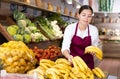 Young female owner of store laying out bananas on display
